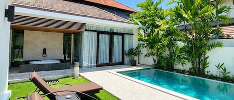 A modern house with a swimming pool, outdoor seating, and a garden.