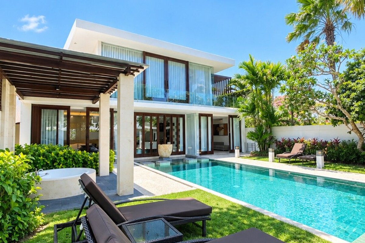 A modern house with a swimming pool, lounge chairs, and a covered patio area.