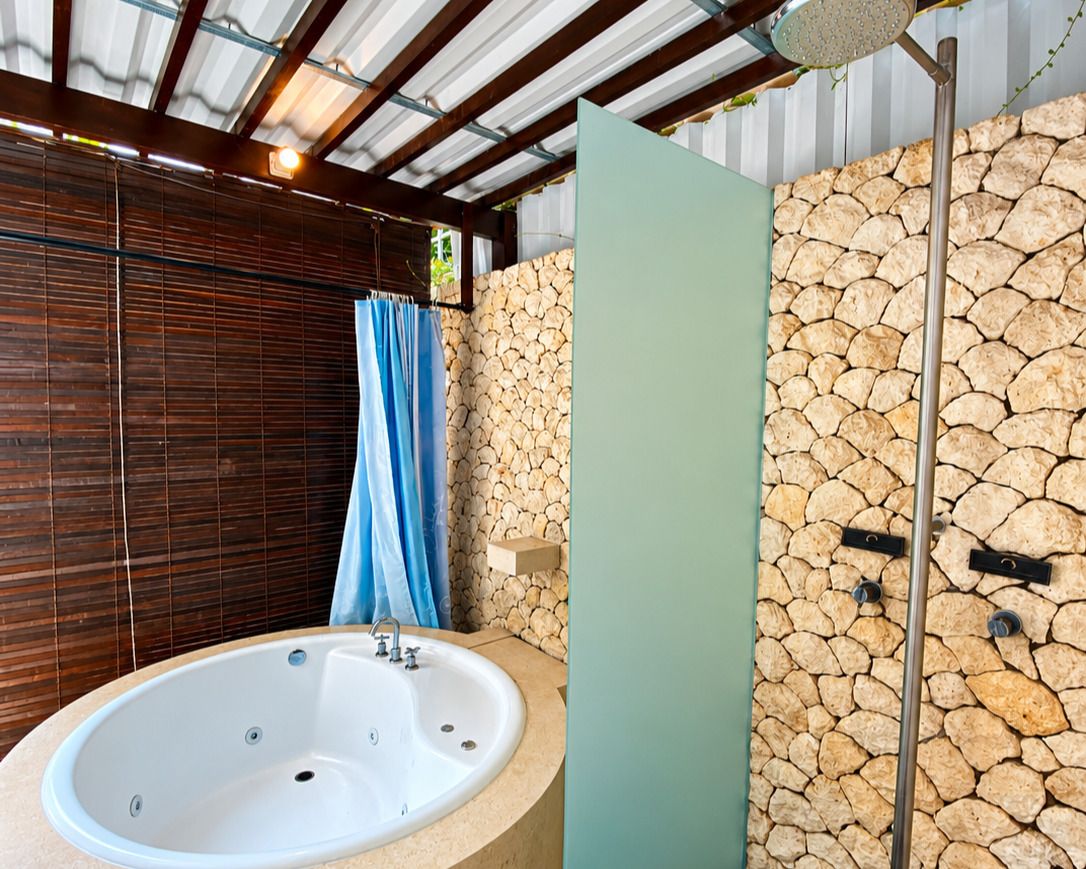 A bathroom with a stone wall, a large bathtub, and a shower area.