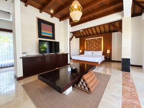 A modern hotel room with a large bed, a flat-screen TV, a wooden coffee table, and a decorative wall piece. - The Wangsa Hotel and Villas Nusa Dua (Nusa Dua)