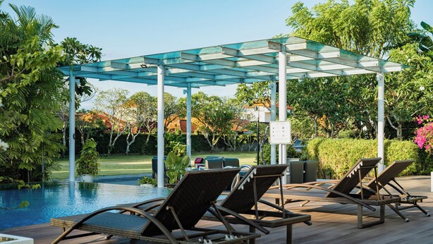 Zona junto a la piscina con sillas de descanso y una pérgola.