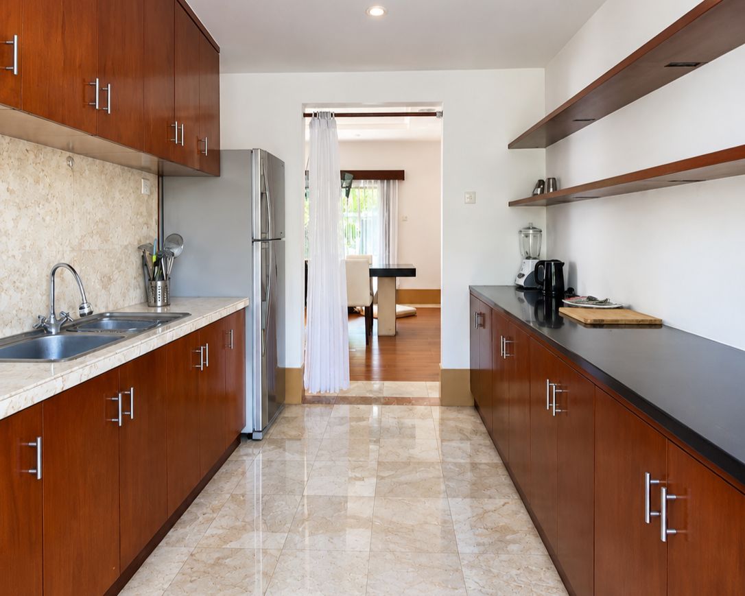 A modern kitchen with wooden cabinets, a stainless steel refrigerator, a sink, and a countertop with a blender.
