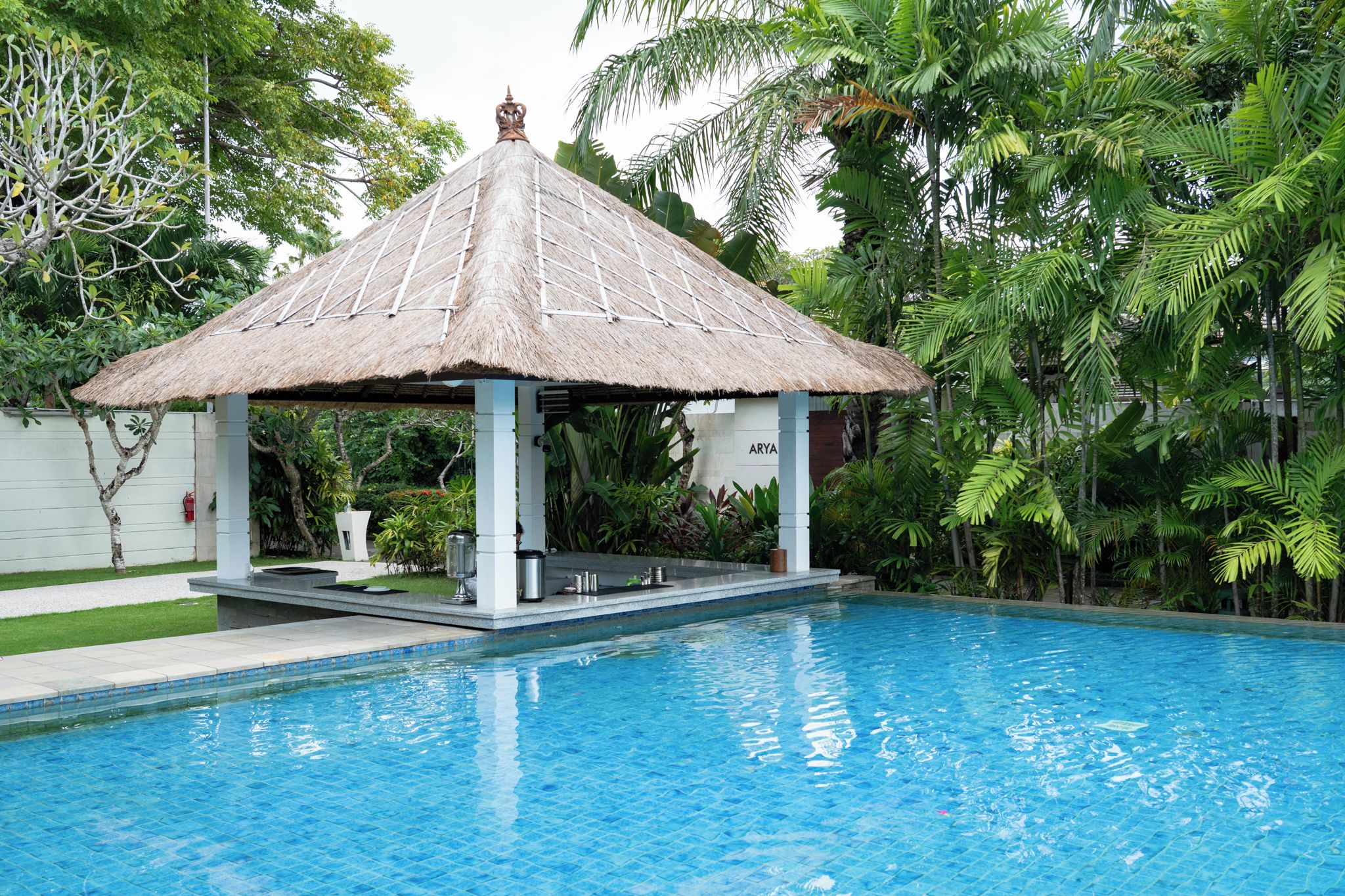 Une piscine avec un kiosque à toit de chaume.