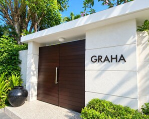 A modern building entrance with a dark wooden door and the name 'GRAHA' on the wall. - The Wangsa Hotel and Villas (Nusa Dua)