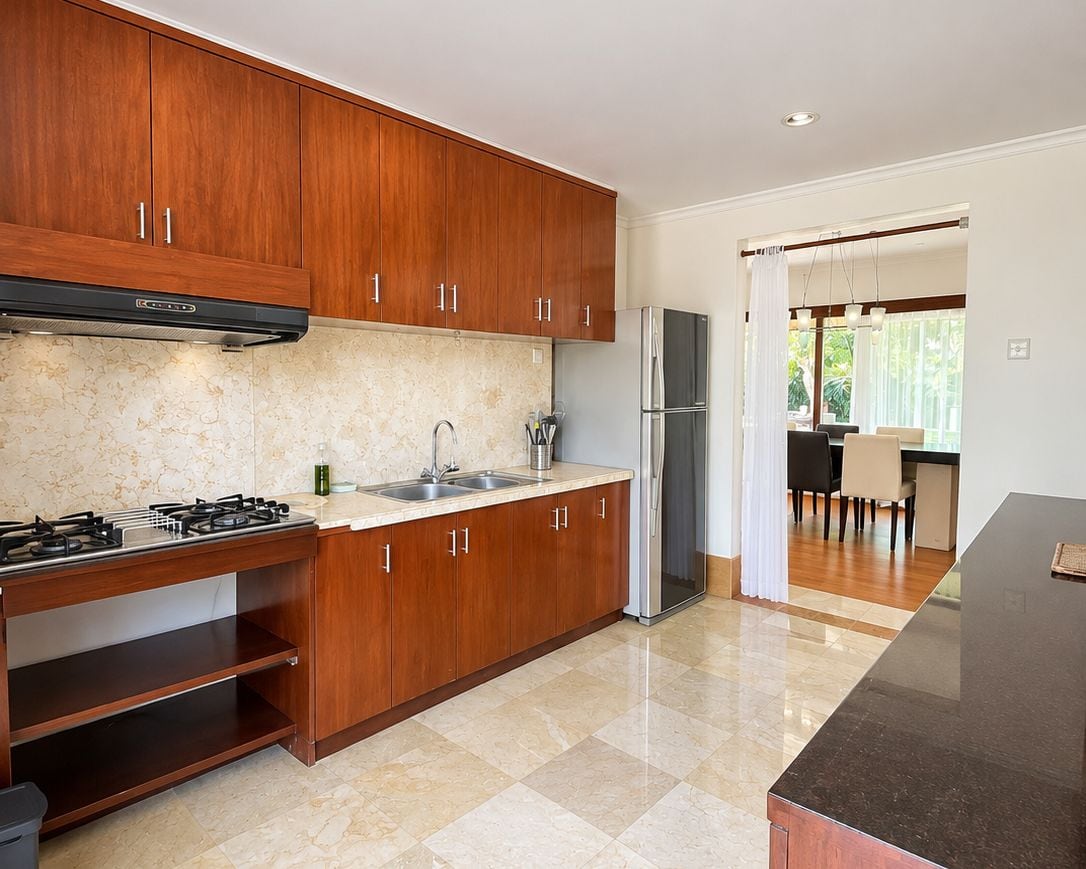 Una cocina moderna con armarios de madera, estufa a gas, refrigerador de acero inoxidable y encimera de mármol.