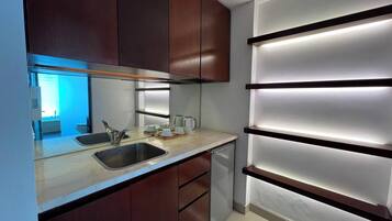 Una cocina moderna con lavavajillas integrado, un fregadero y una encimera con cafetera y tazas.