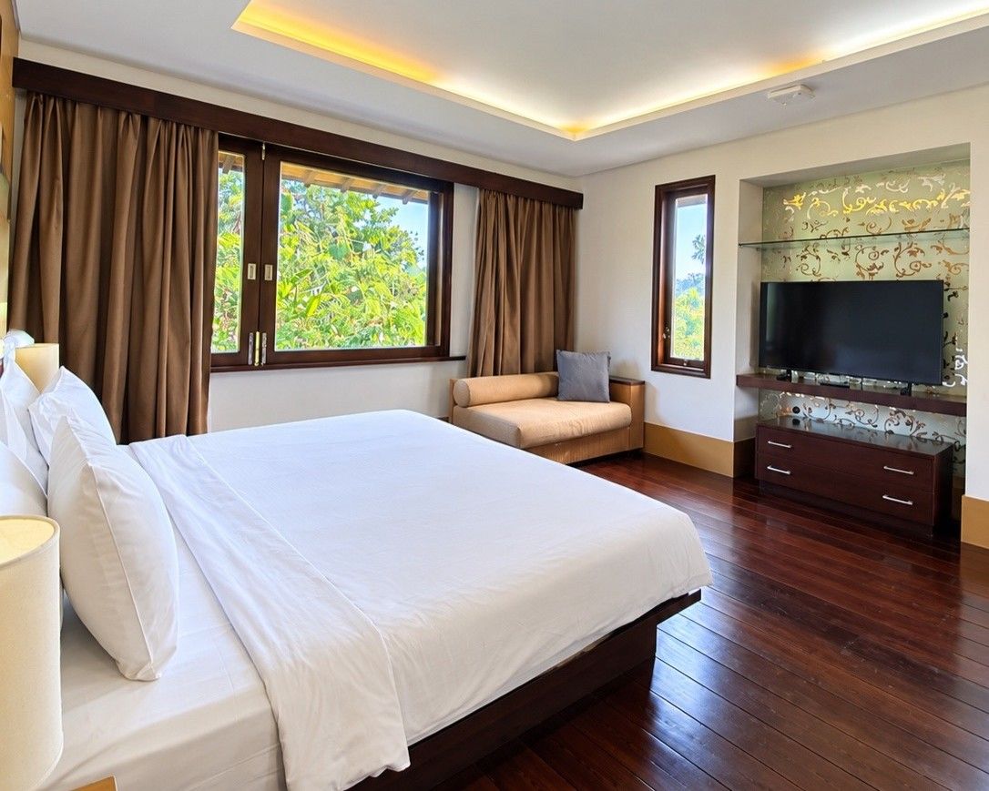 Habitación de hotel con una cama grande, un sofá, un televisor y un armario.