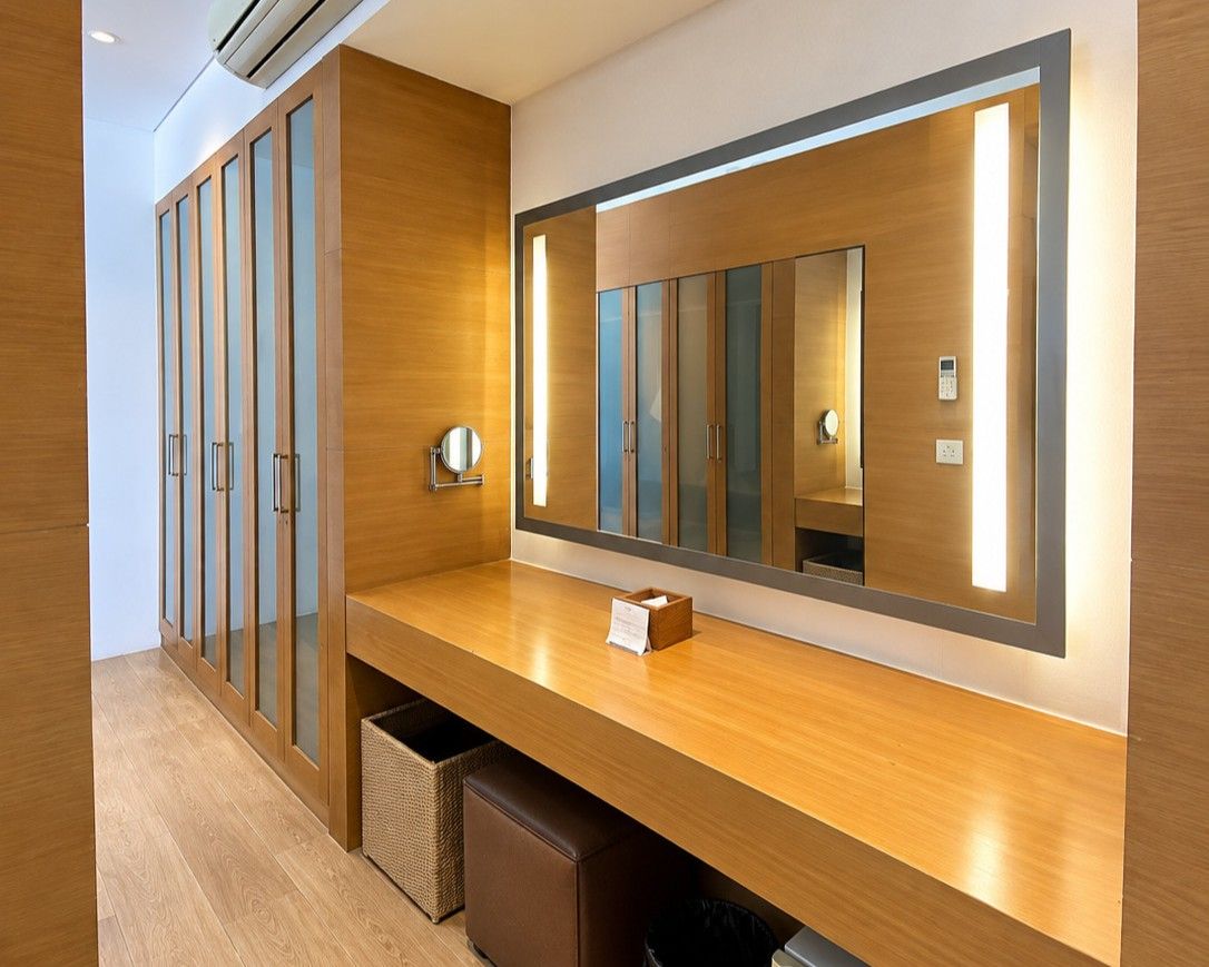 Habitación de hotel con tocador de madera, un espejo grande y un armario empotrado con puertas correderas.