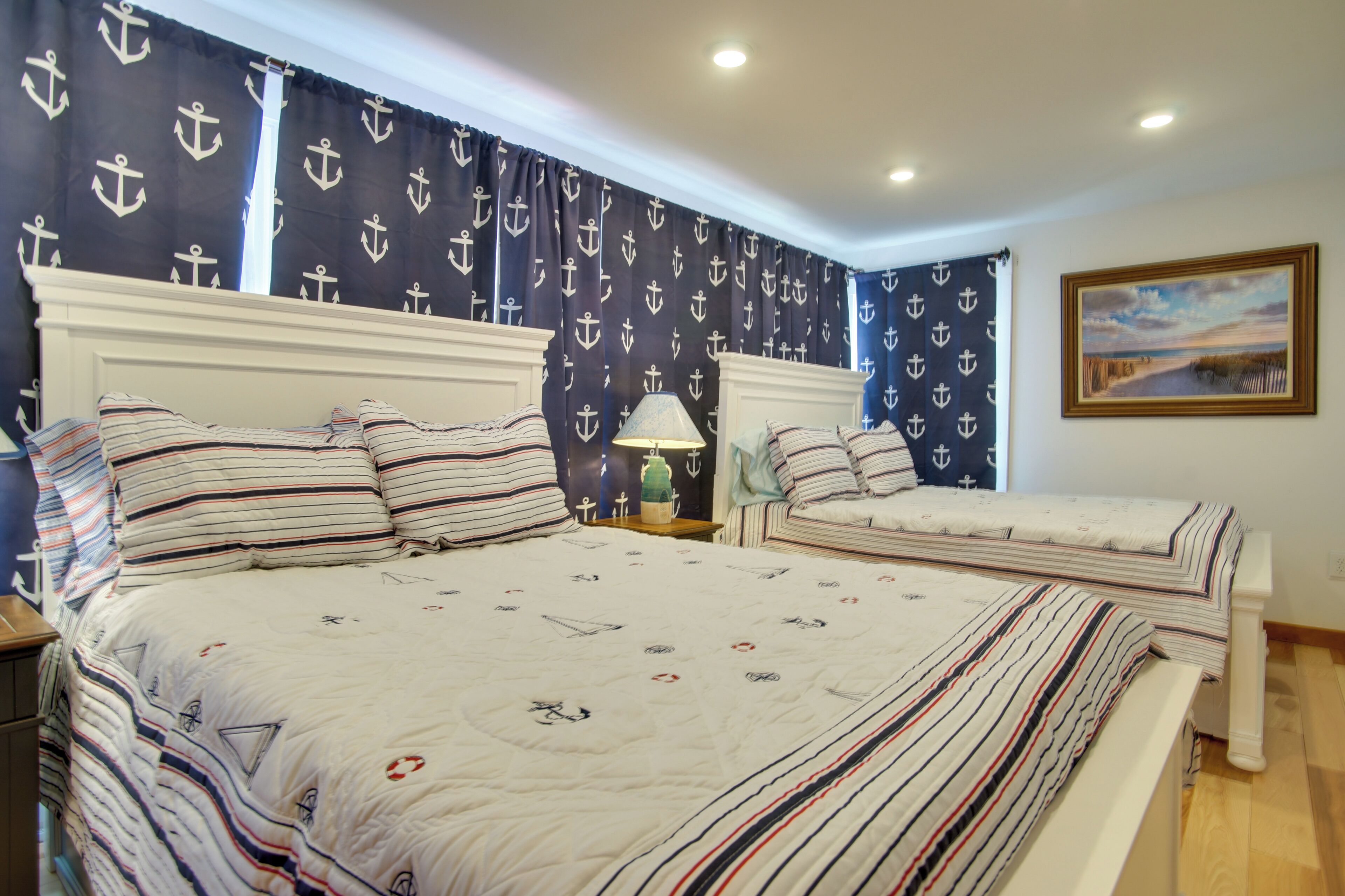 Una cama doble con ropa de cama a rayas y un detalle decorativo con tema náutico en la pared.