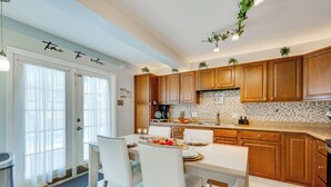 A modern kitchen with wooden cabinets, a dining table set for four, and a 'time to relax' sign on the door. - Group-Ready Oasis w/ Pool & Games in Port Richey (Port Richey)
