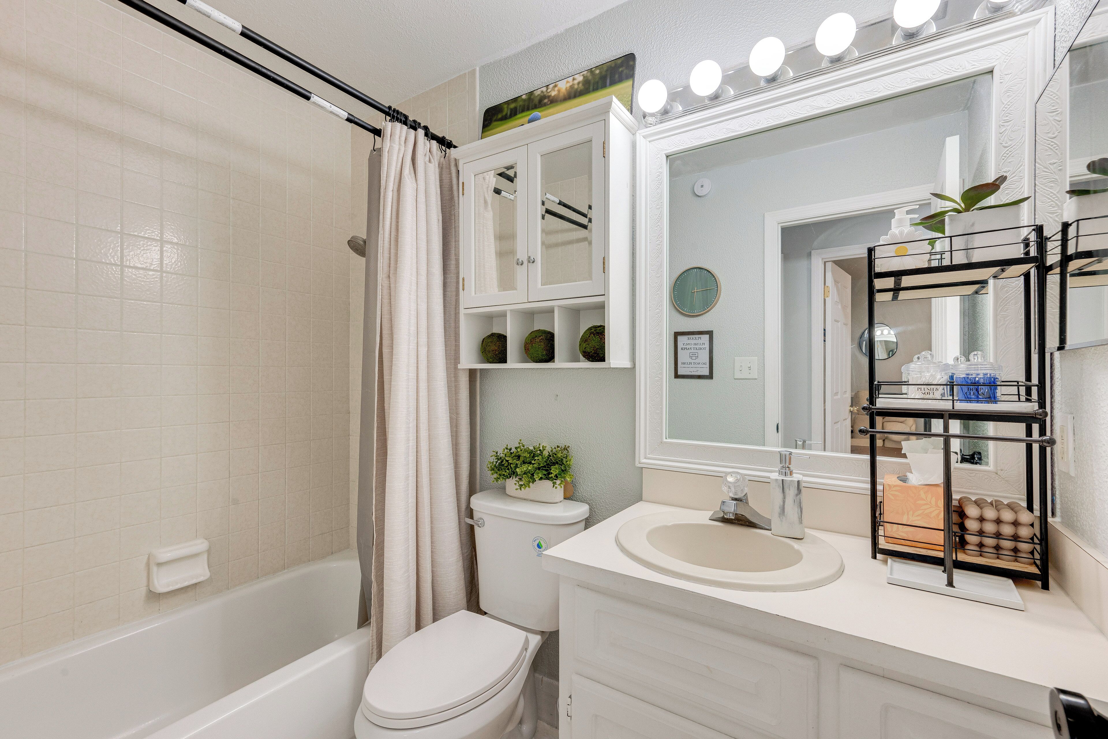 Une salle de bain comprenant une baignoire, des toilettes, un meuble-lavabo et un miroir avec éclairage.
