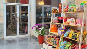 A snack display with various packaged goods, a potted plant, and a glass door entrance.