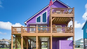 A two-story building with a balcony and a deck, featuring a flagpole with an American flag. - Walk to Ocean! Crystal Beach Gem w/ Decks & View! (Crystal Beach)