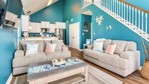 A living room with two sofas, a coffee table, and a kitchen in the background. - Walk to Ocean! Crystal Beach Gem w/ Decks & View! (Crystal Beach)