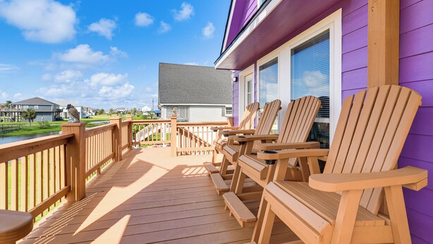 A wooden deck with Adirondack chairs and a view of houses in the background. - Walk to Ocean! Crystal Beach Gem w/ Decks & View! (Crystal Beach)