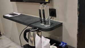 Minibar com cafeteira, água engarrafada e um pequeno frigorífico.