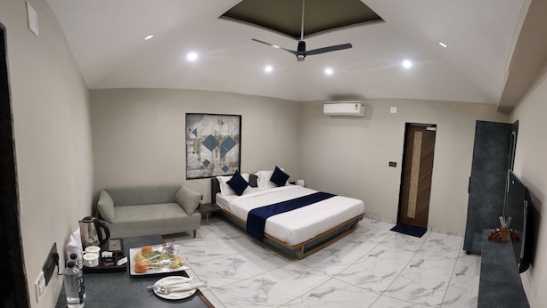 Quarto de hotel moderno com cama, sofá, escrivaninha e televisão de tela plana.