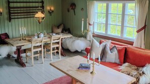 A cozy room with a wooden table, chairs, a sofa, and a window with curtains.