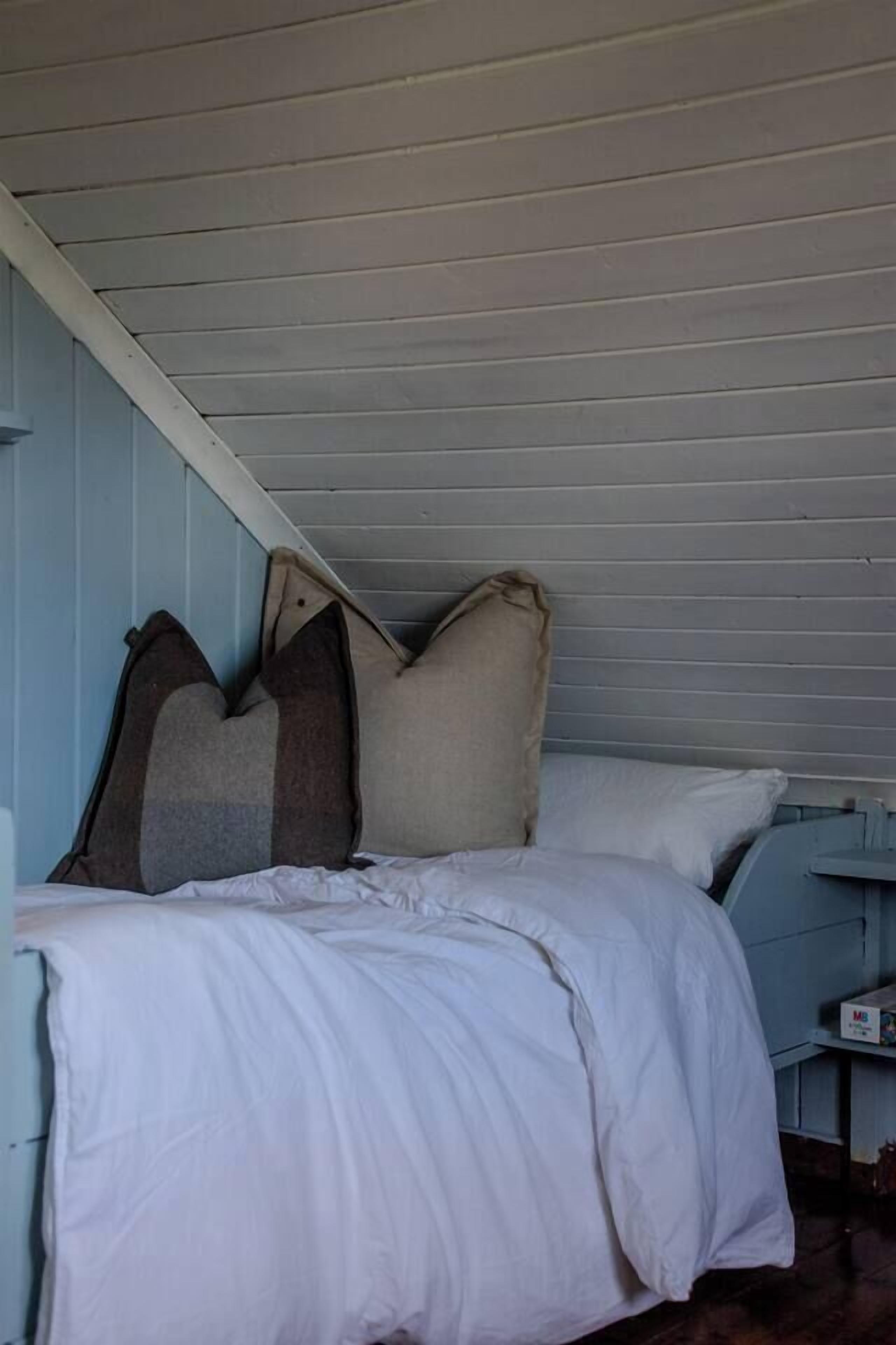 A bedroom with a bed, pillows, and a small table with a box.