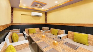 A dining area with a long table, multiple seating options, and ceiling fans.