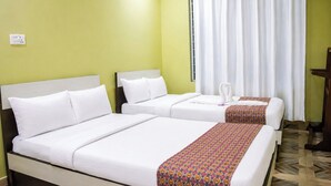 A hotel room with two beds, a window with curtains, and a patterned rug.
