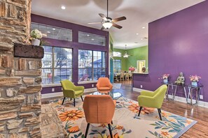 Una sala de estar moderna con una pared de acento de piedra, ventanas amplias y un colorido tapiz floral.
