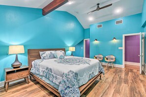 Un dormitorio con cama, mesitas de noche, ventilador de techo y una puerta.