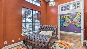 A bedroom with a tufted leather bed, a large window, and a butterfly mural on the door. - Private Pool: Spacious & Vibrant Argyle Villa! (Argyle)