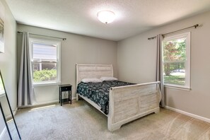 Ein Schlafzimmer mit einem Bett, zwei Fenstern, einer Deckenleuchte und Teppichboden.