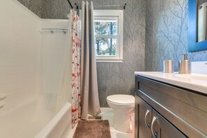 Ein Badezimmer mit Dusche, Toilette und Waschtisch mit Spiegel.