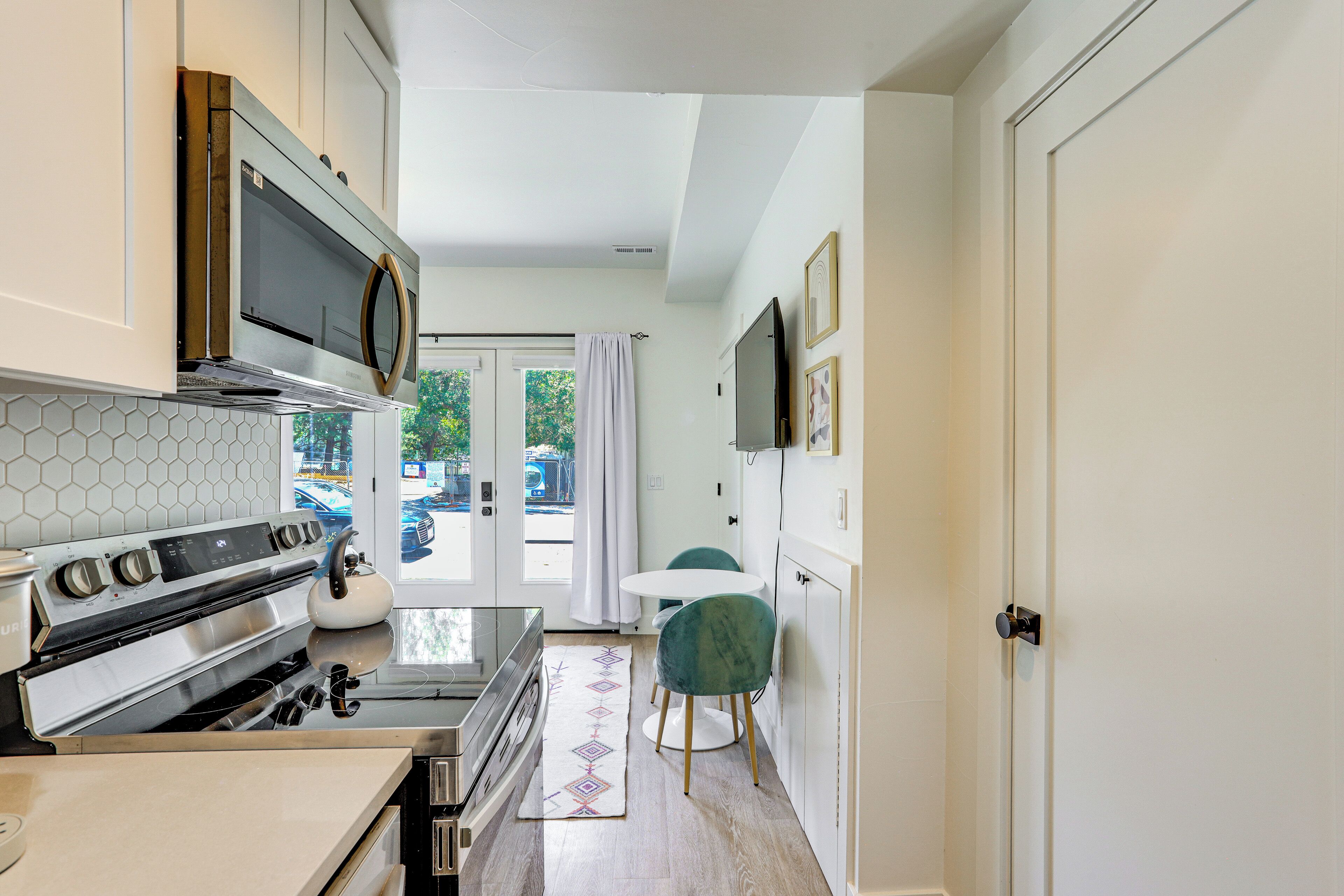 A compact kitchen with a microwave, stove, and dining area with a table and chairs.
