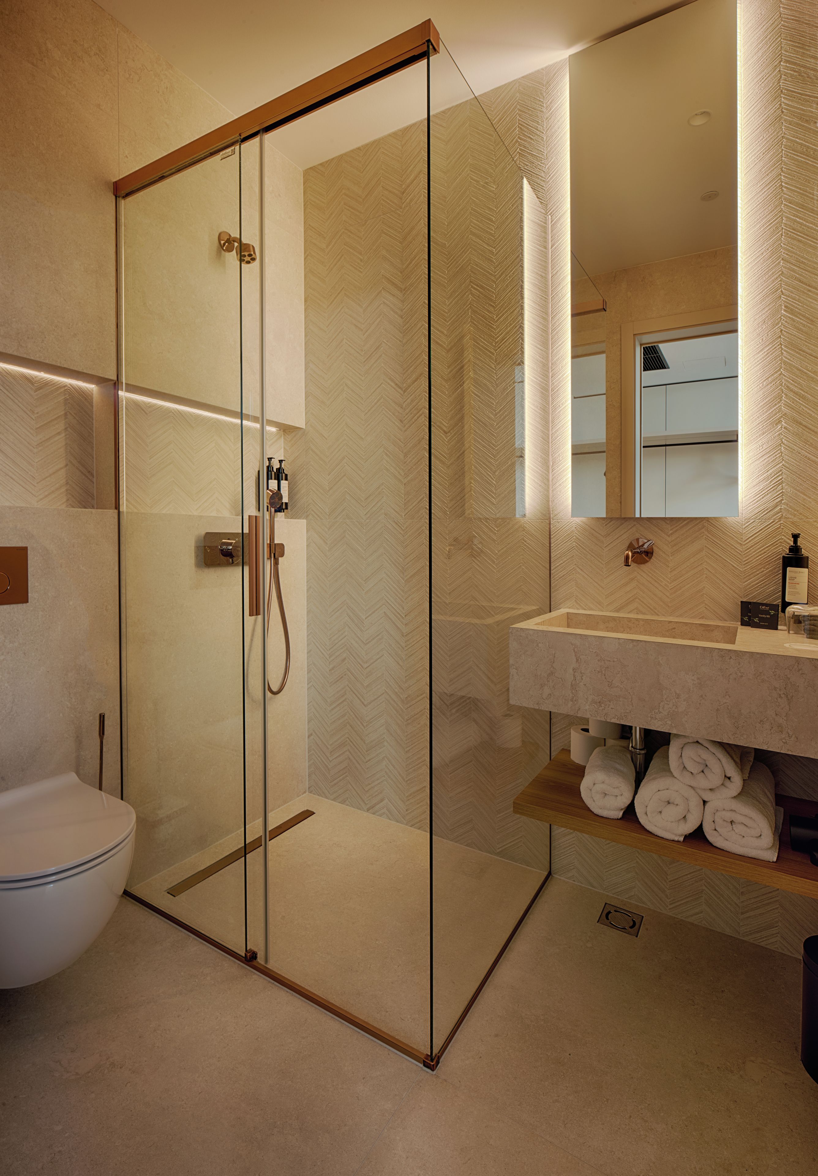 Ein modernes Badezimmer mit einer Duschkabine, einer weißen Toilette und einem Waschtisch mit Handtüchern.