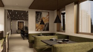 A modern dining area with a high ceiling, pendant lighting, and a large abstract painting.