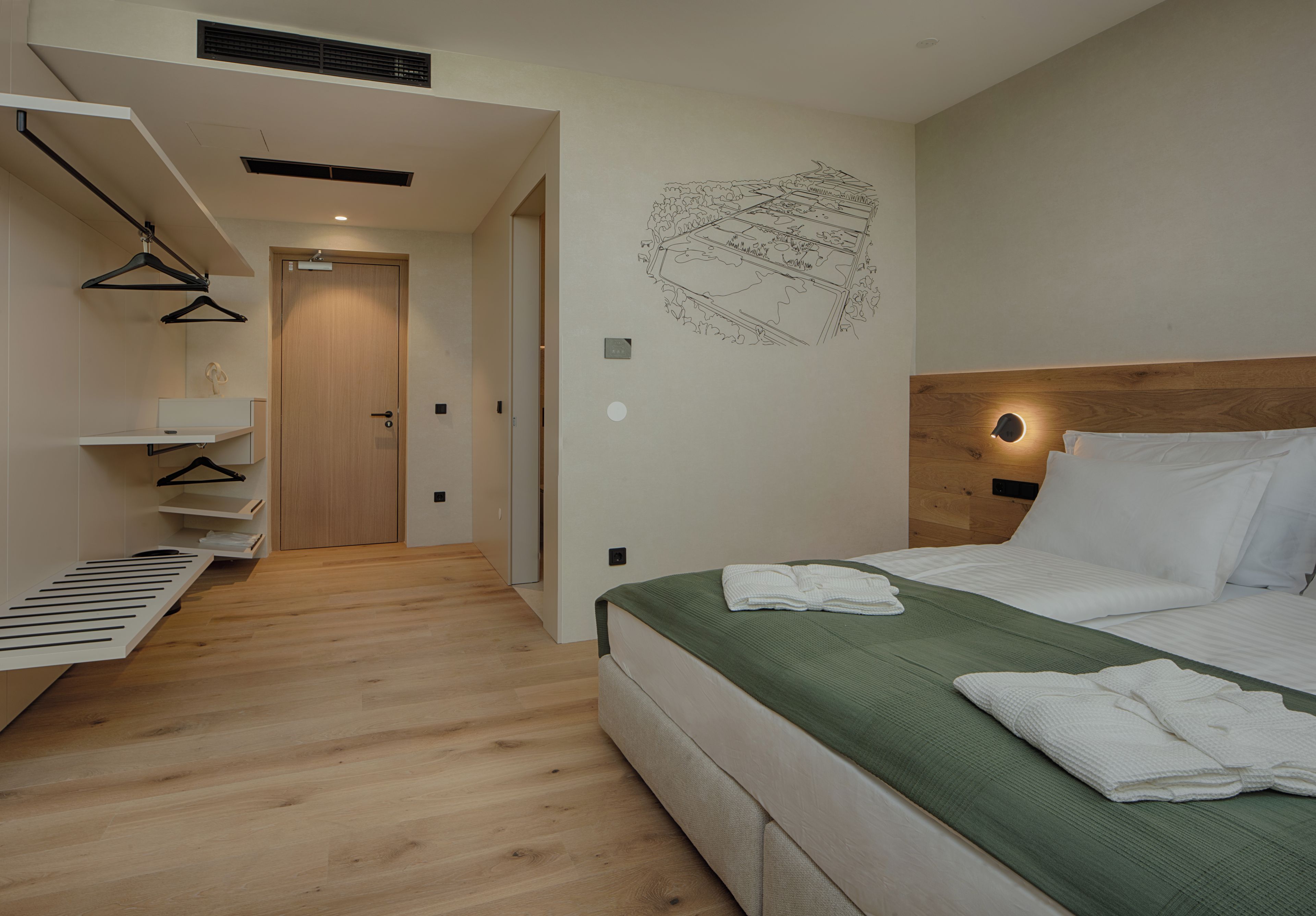 Habitación de hotel moderna con cama, suelo de madera, calentador de pared y perchero.