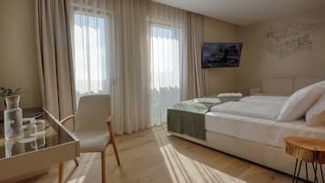 A hotel room with a bed, a desk, a chair, and a television on the wall.