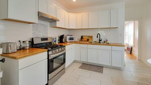 A modern kitchen with white cabinets, a wooden countertop, a stove, a microwave, and a sink. - Pool Table! Pet-Friendly Haven 6 Mi to Rate Field (Chicago)