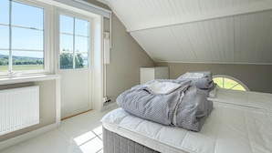 Un dormitorio con cama, ventana, radiador y una mesita de noche.