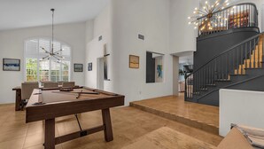 A spacious room with a pool table, a staircase, and a view of the outdoors. - Desert Sanctuary | Pool, Spa & Sleeps 12 (Indio)