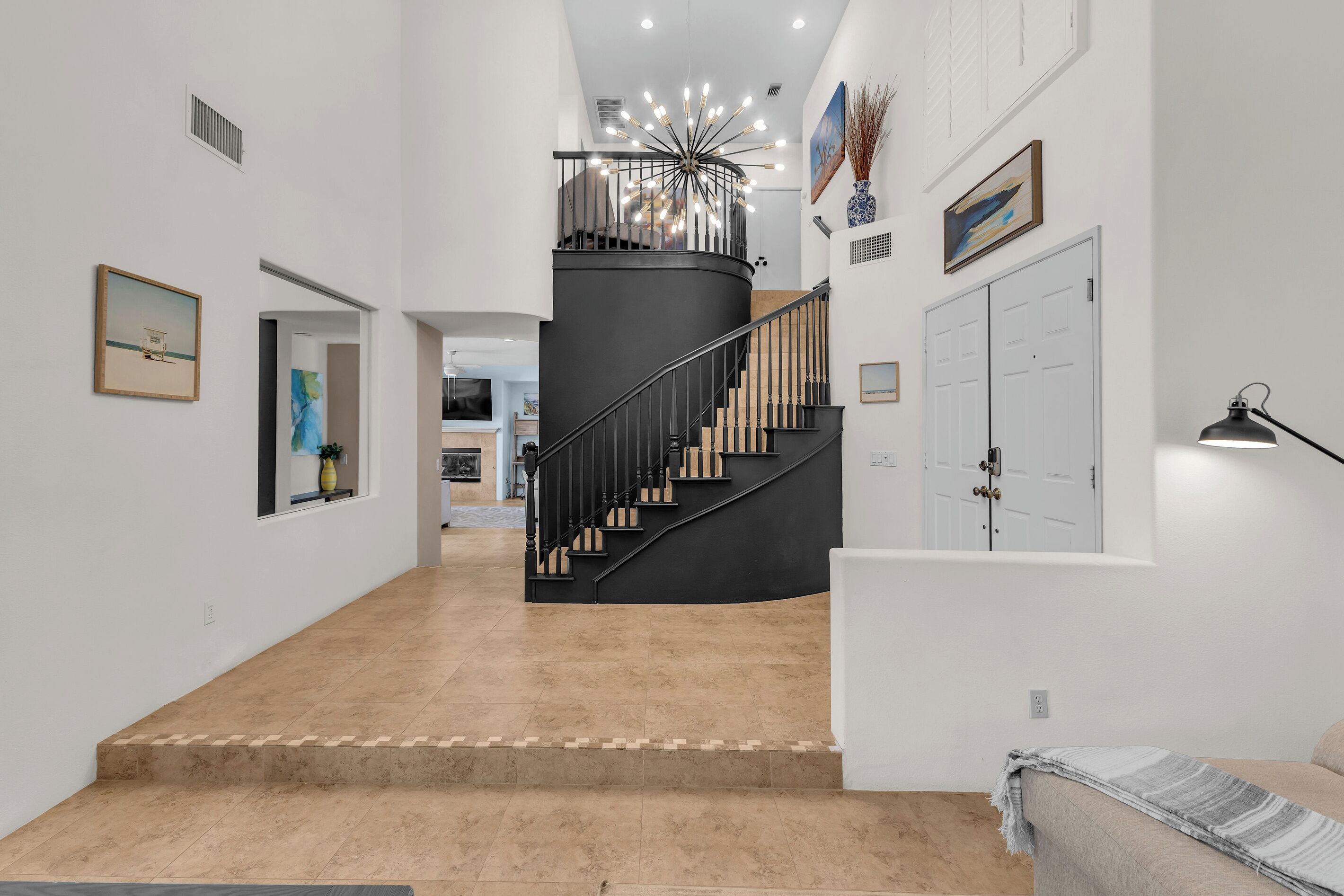 A modern interior with a curved staircase, a chandelier, and a sofa.