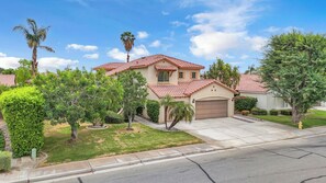 A two-story house with a red-tiled roof, a garage, and a well-maintained lawn. - Desert Sanctuary | Pool, Spa & Sleeps 12 (Indio)