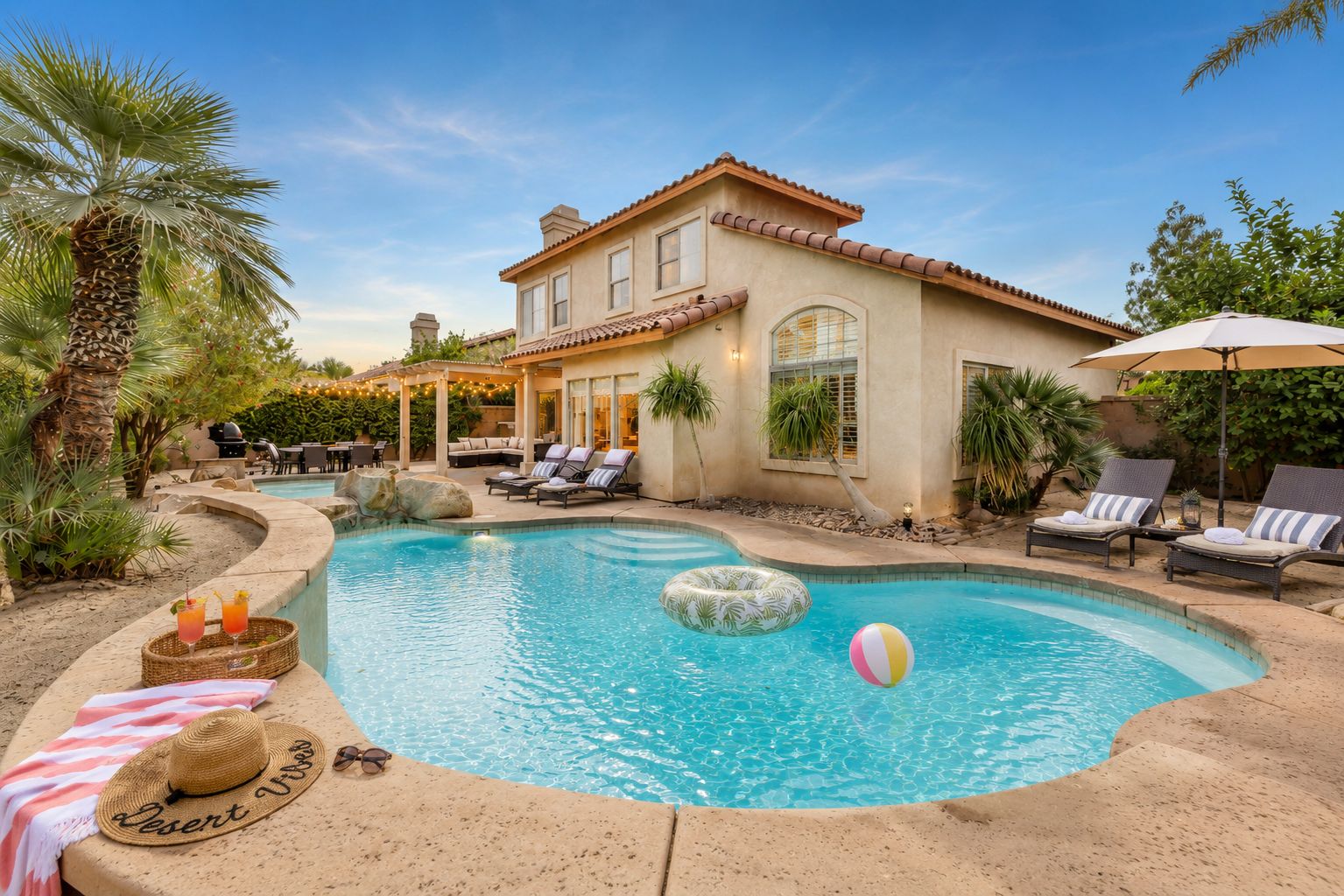 A pool area with lounge chairs, a floating ring, and a beach ball.