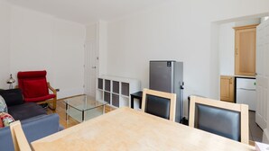 Een moderne woonkamer met een glazen salontafel, een rode stoel en een tweepits fornuis.