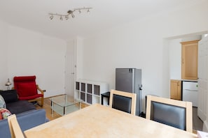 Ein modernes Wohnzimmer mit einem Glastisch, einem roten Sessel und einem Zweiflammenkocher.