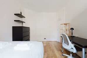 Ein Schlafzimmer mit Bett, Schreibtisch, Stuhl und Kleiderschrank.