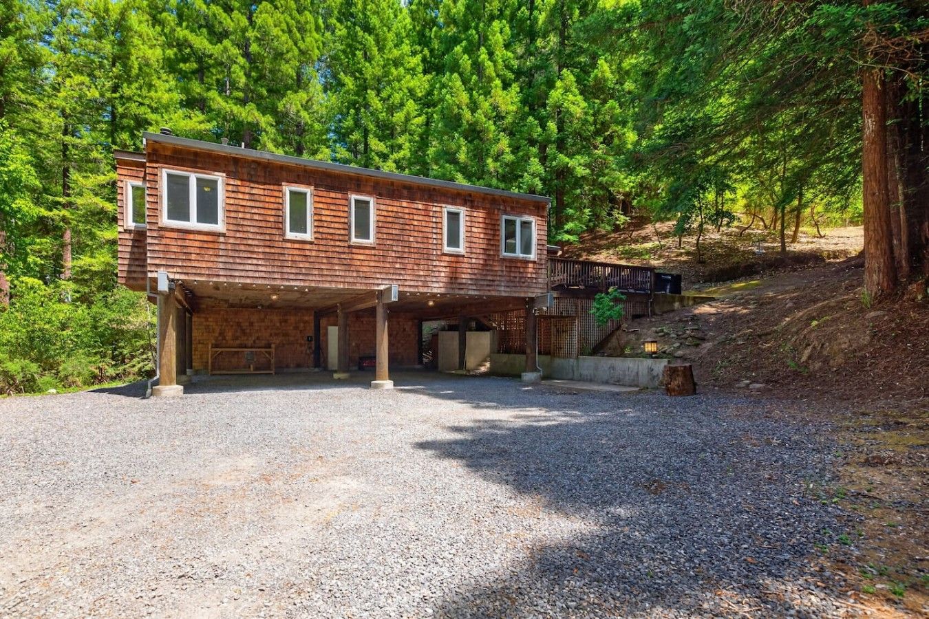 A two-story wooden cabin with a covered garage and a deck.