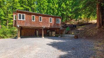 A two-story wooden cabin with a covered garage and a deck.