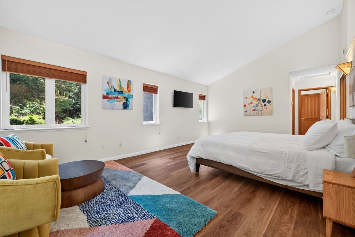 Une chambre à coucher avec un lit, un canapé, une télévision et des œuvres d’art accrochées aux murs.