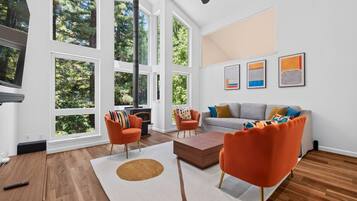 A spacious living room with large windows, a fireplace, and modern furniture.