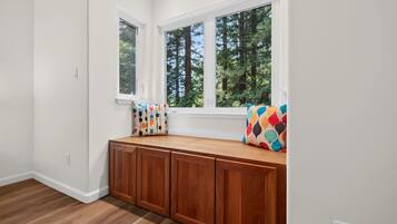 A room with a built-in bench against a wall with large windows overlooking a forest.