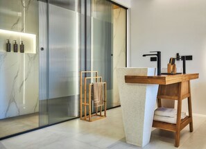 A modern bathroom with a marble vanity, a glass shower enclosure, and a wooden towel rack. - Diastar Luxury Suite in Heraklion Crete A3 (Xeropotamos)